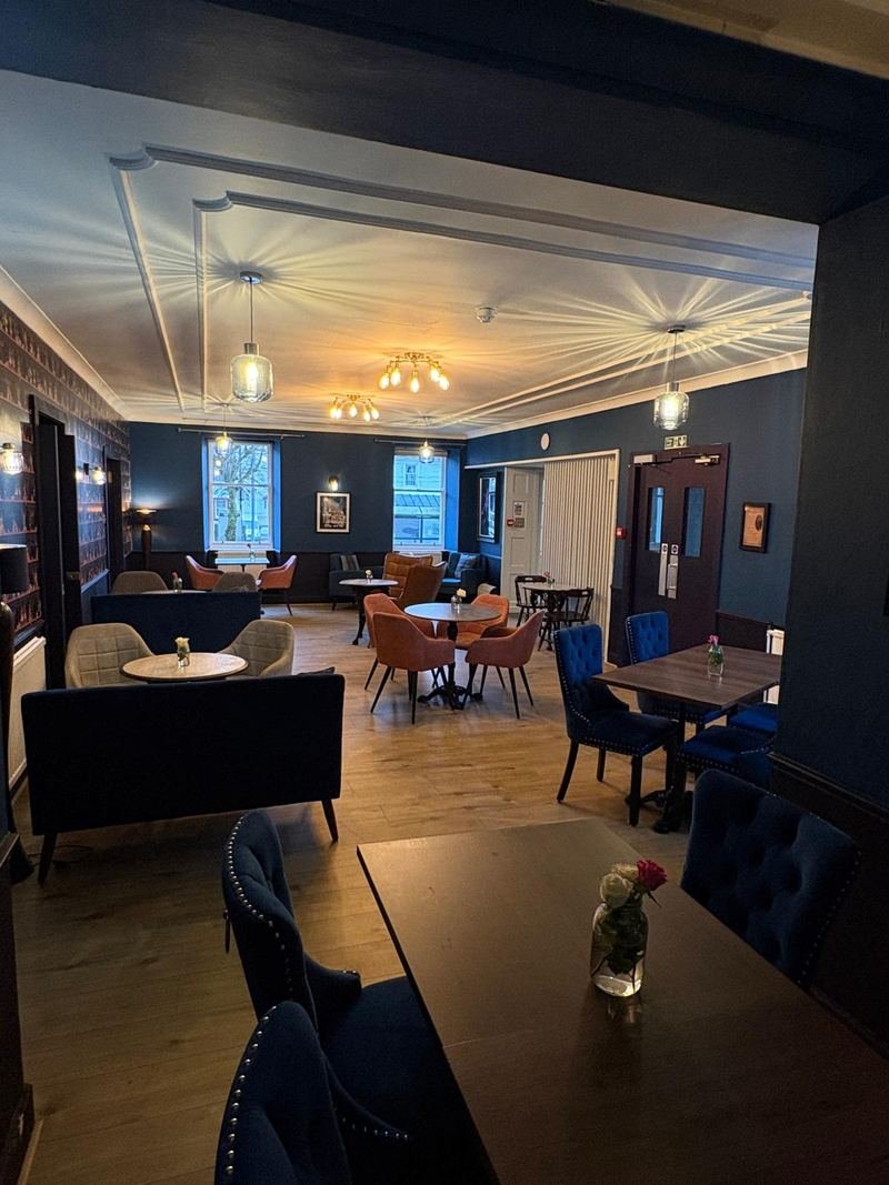 The bar lounge, sofas and armchairs, tall windows at the far end