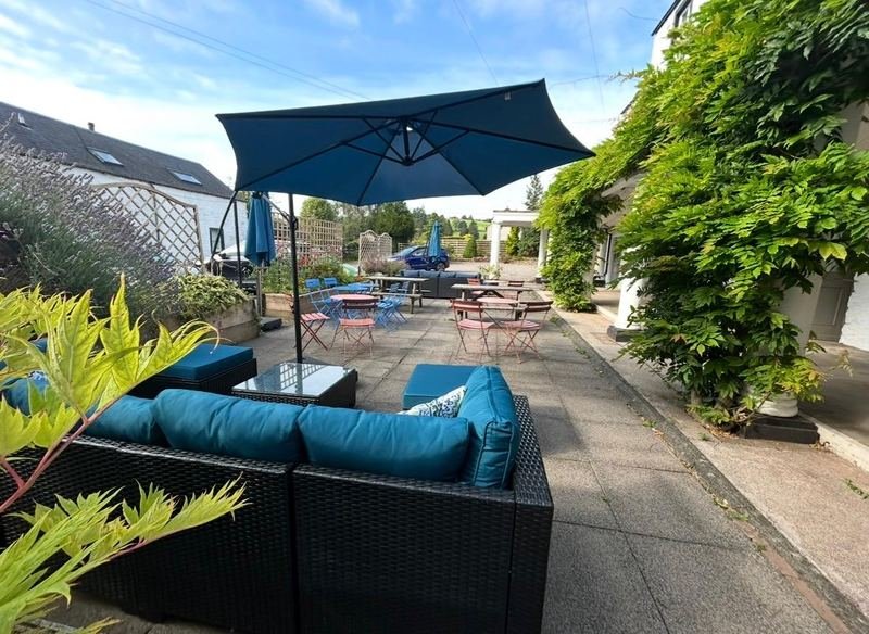 The courtyard in summer, with sofas, parasols and wisteria
