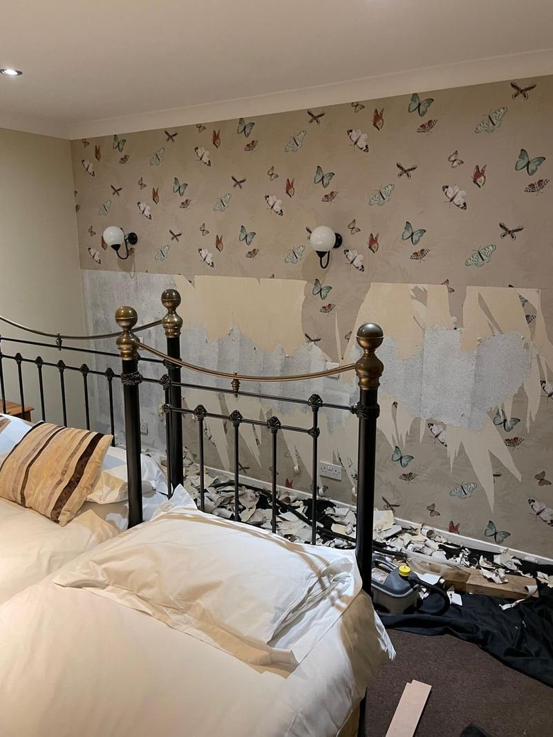 Old butterfly wallpaper half stripped off a bedroom wall