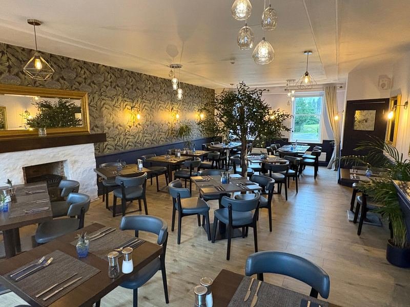 The restaurant: thistle wallpaper, wooden tables laid for dinner, a fireplace and a tree in the corner