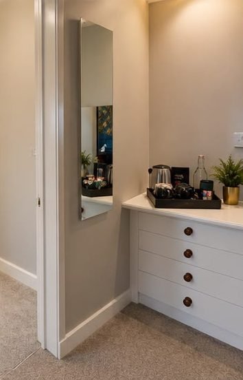 A dressing table with a tea and coffee tray and a long mirror